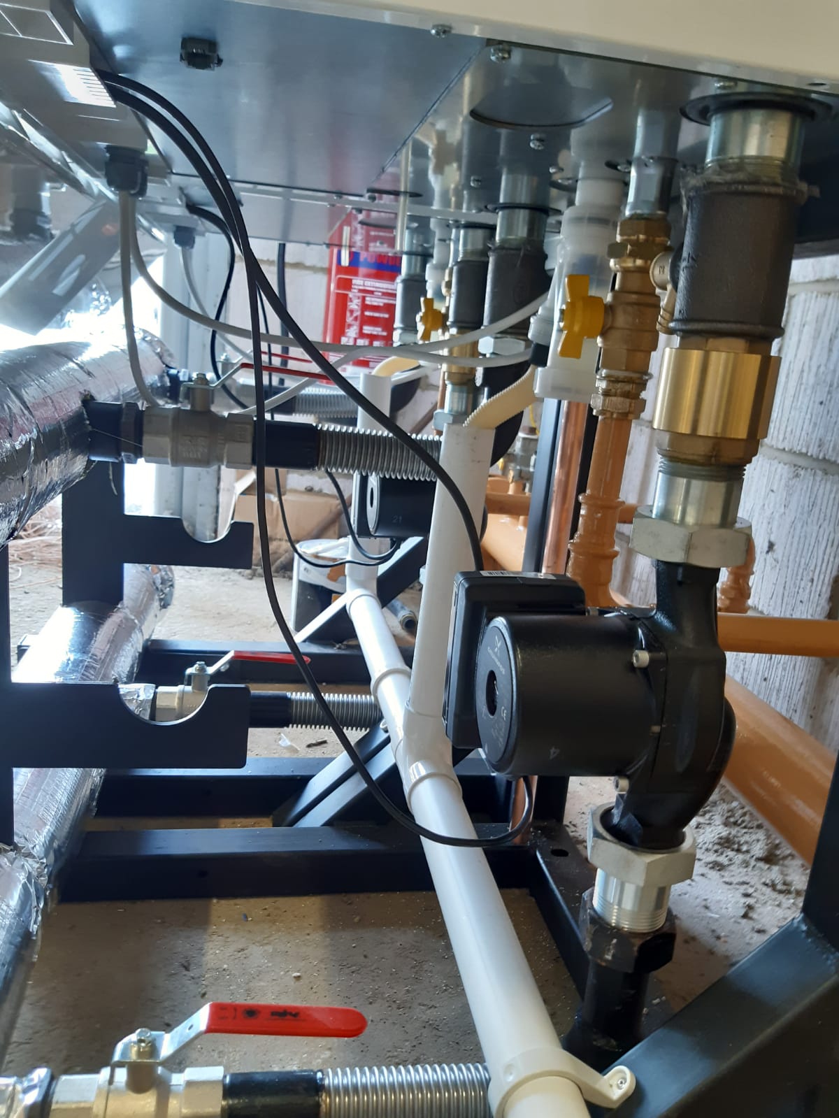 Pump, valves and brass fittings on the pipework under a boiler frame